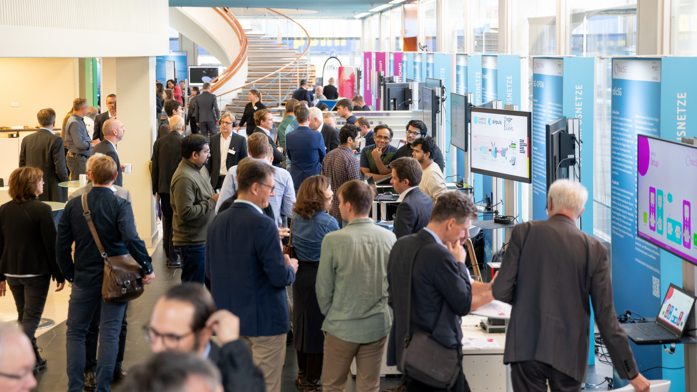 Besucherinnen und Besucher tauschen sich im Ausstellungsbereich der Tage der digitalen Technologien aus.