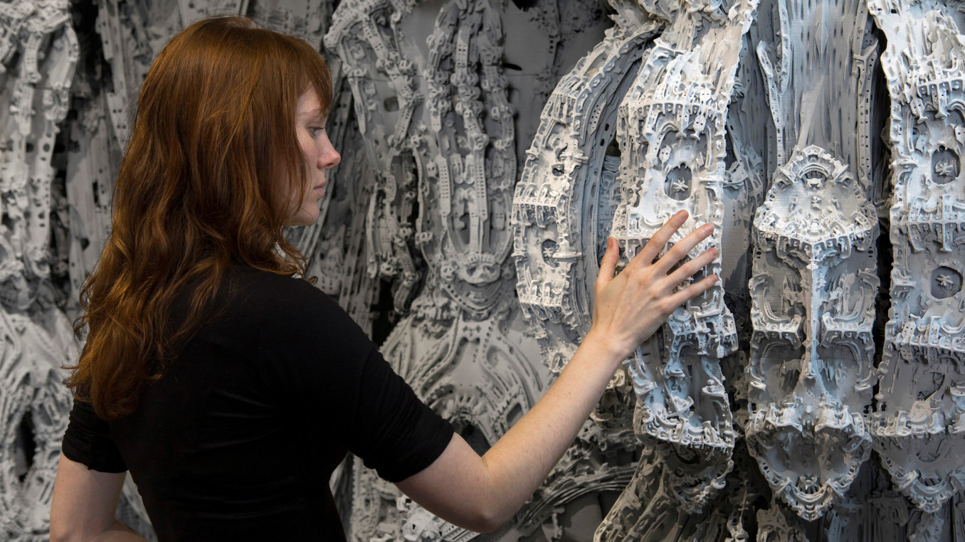 Das Bild zeigt eine Frau vor einem 3D gedrukten Architekur-Objekt.
