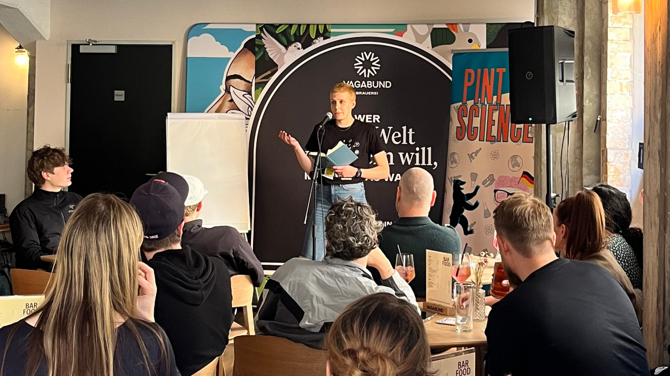 Scientist gives talk in front of crowd in a bar.