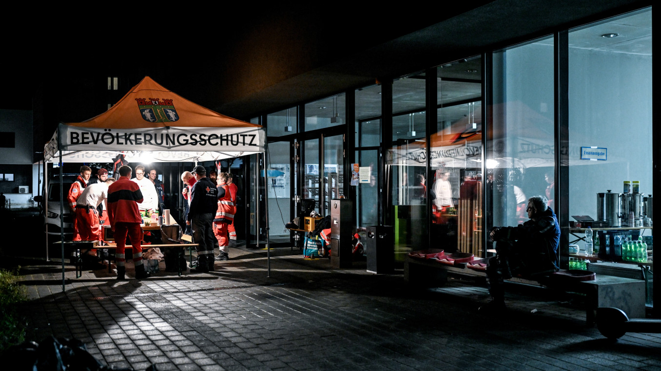 Zelt mit der Aufschrift "Bevölerkungsschutz" auf einer dunklen Straße neben einem schwach beleuchteten Gebäude. 