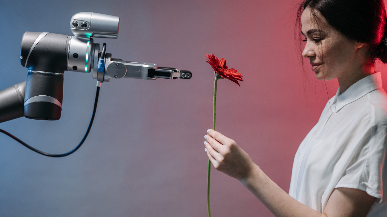 Roboterarm reicht einer Person eine Blume