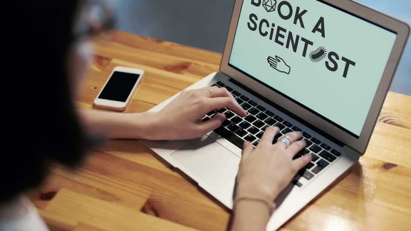Das Foto zeigt ein Bild eines Laptops mit dem Hinweis auf Book a Scientist