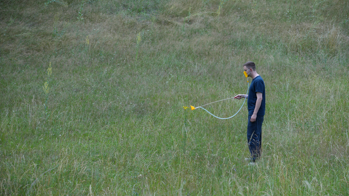 Eine Person trägt eine Geruchsprothese und folgt damit einer Spur über eine Wiese