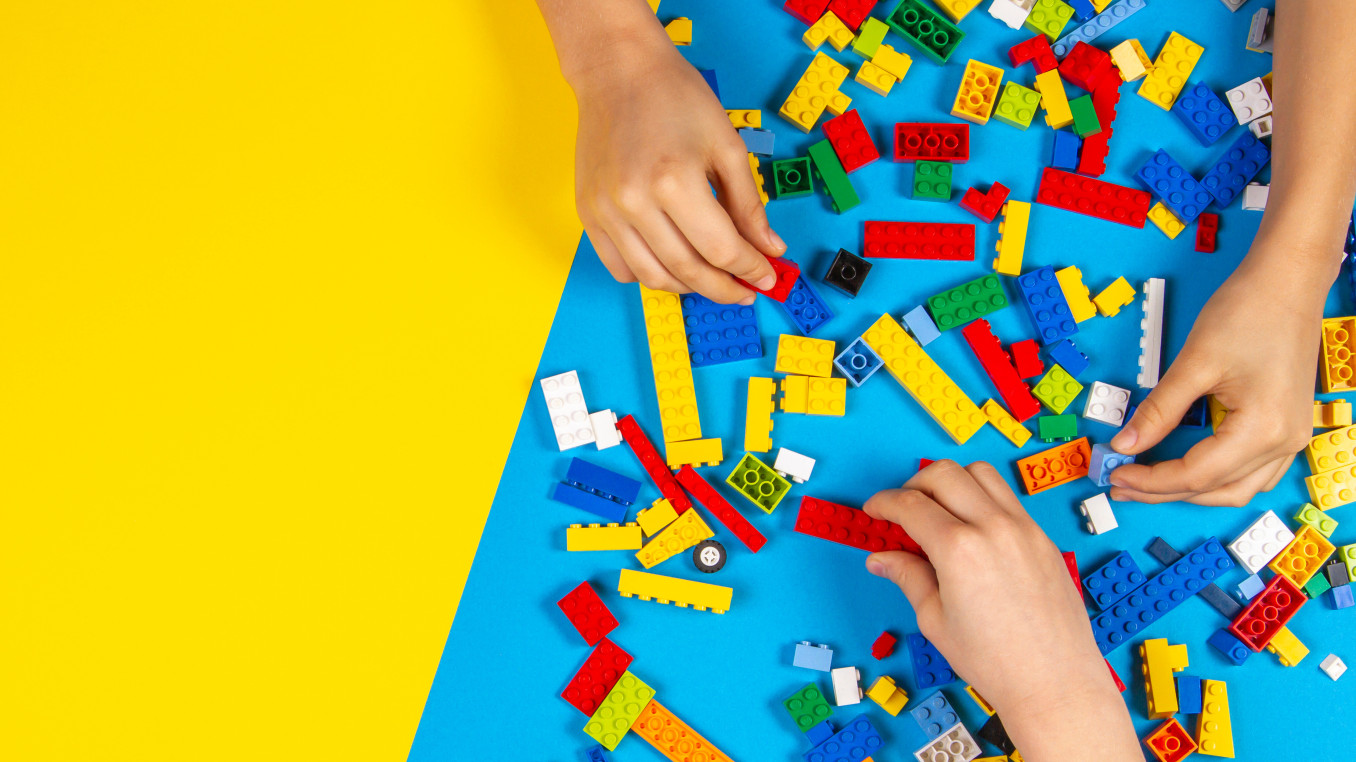 Children's hands playing with colorful Lego bricks