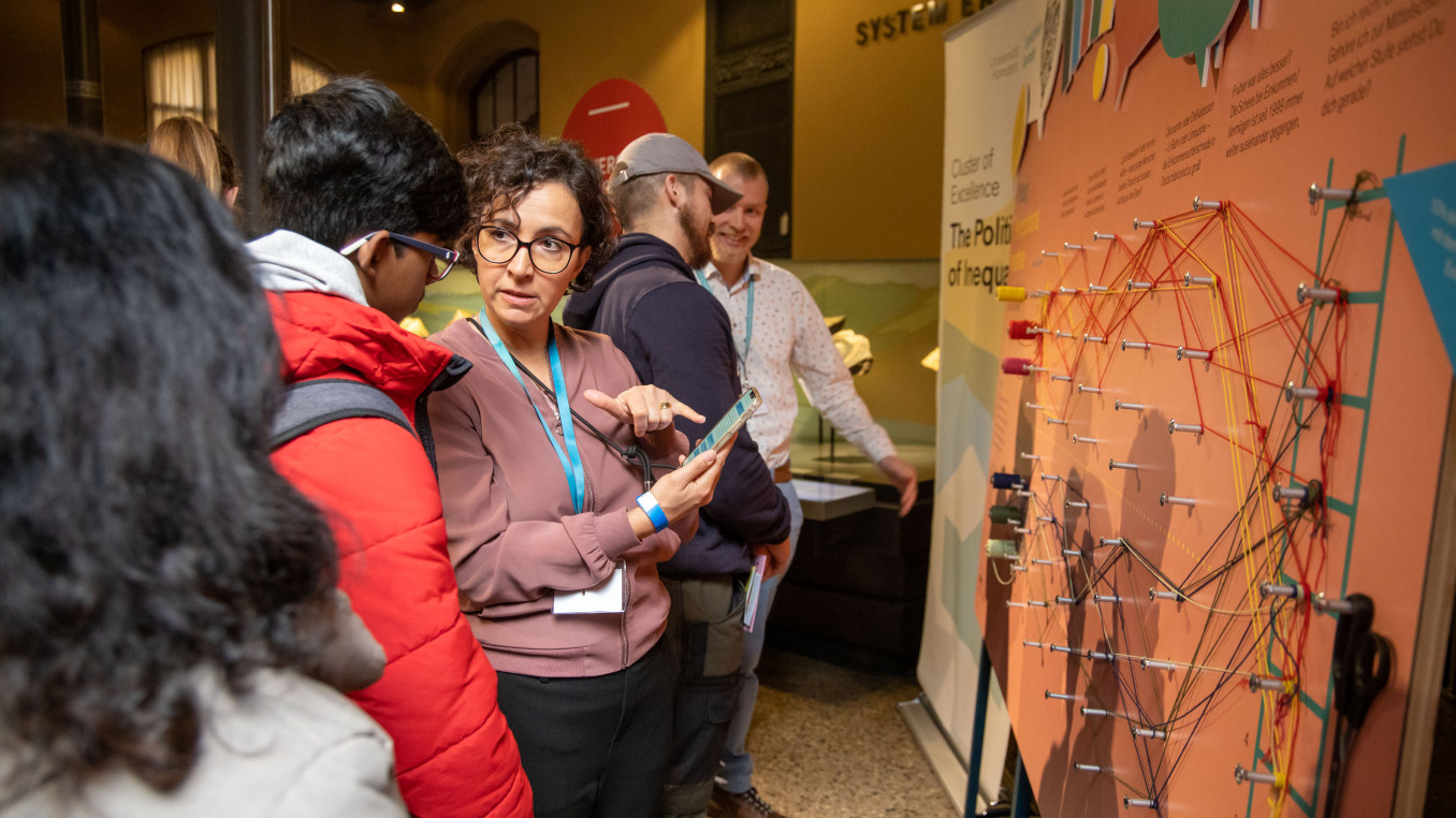 Am Stand des Exzellenzclusters auf der Berlin Science Week 2024 wird Besuchern das Projekt erklärt.